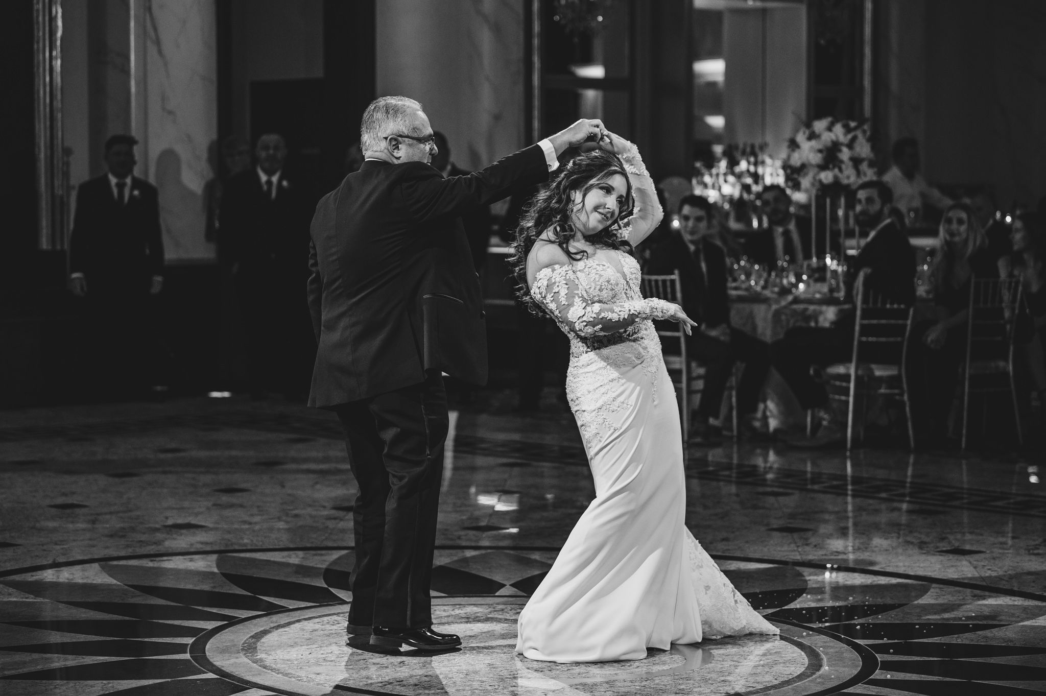 Dancers twirl gracefully on an ornate ballroom floor during an evening celebration.