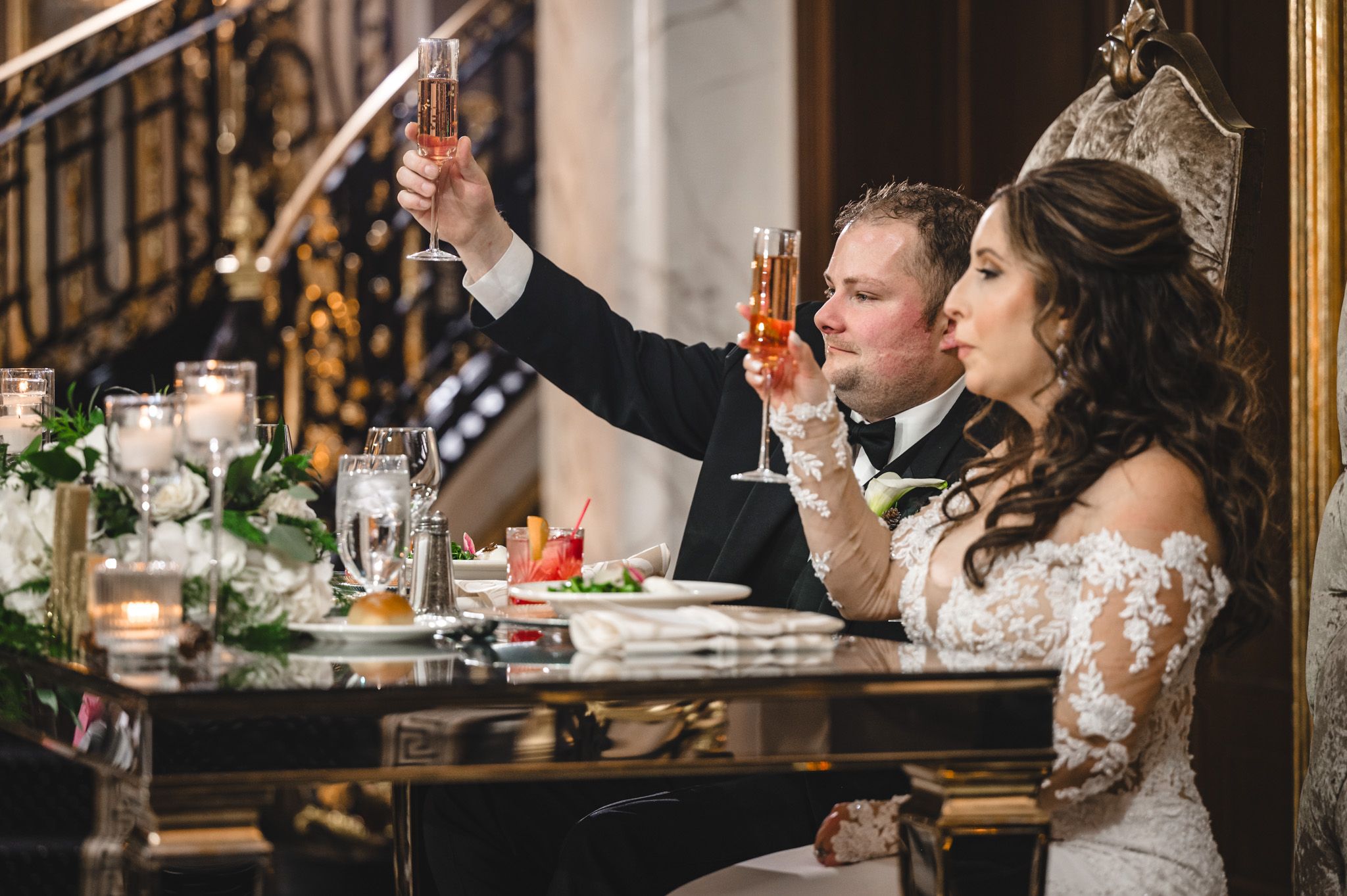 Couple shares laughter during their wedding reception at a luxuriously decorated venue.
