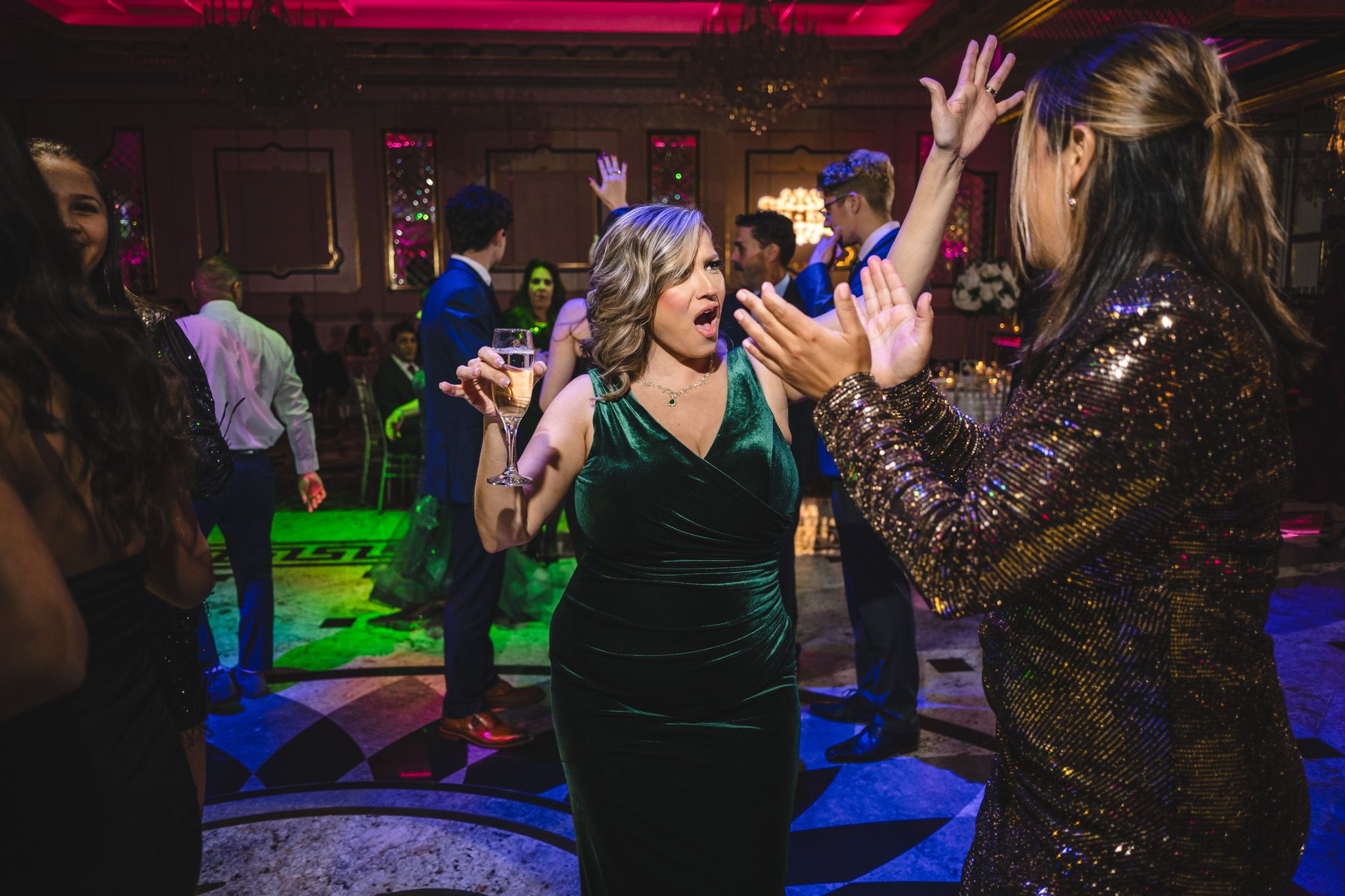 Party guests dancing under colorful lights at a lively wedding reception.