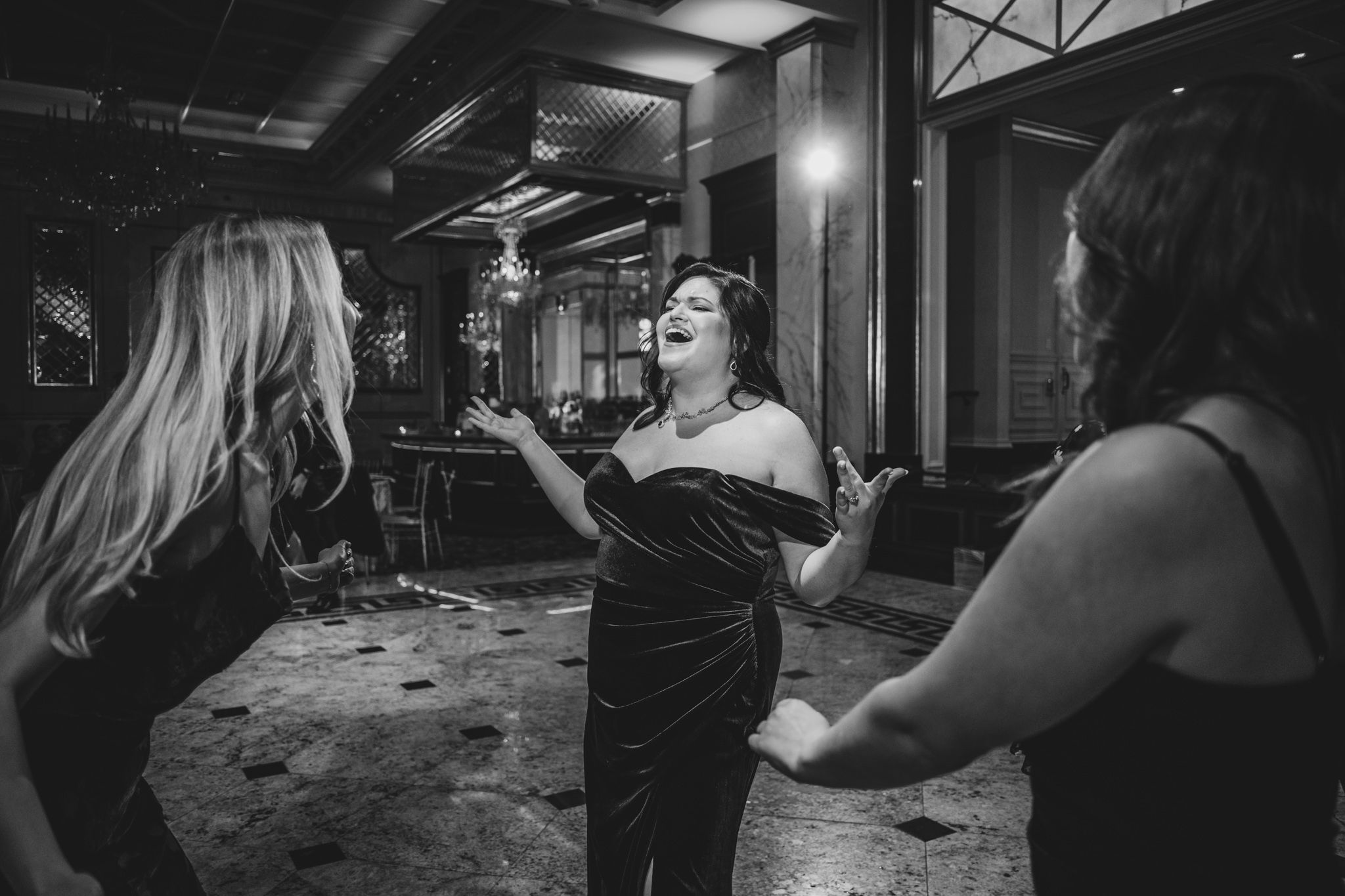 Black and white photo of guests dancing and celebrating at a nighttime wedding reception.