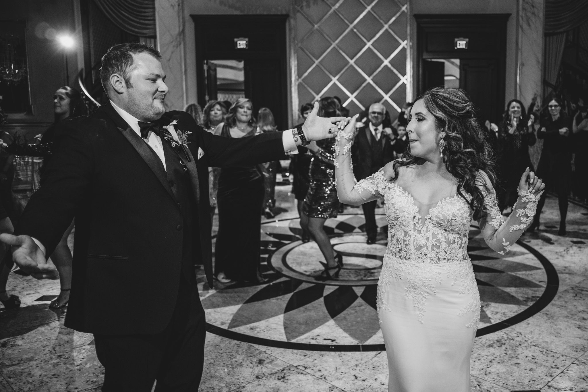 Guests celebrate on a patterned dance floor during an elegant evening wedding reception.
