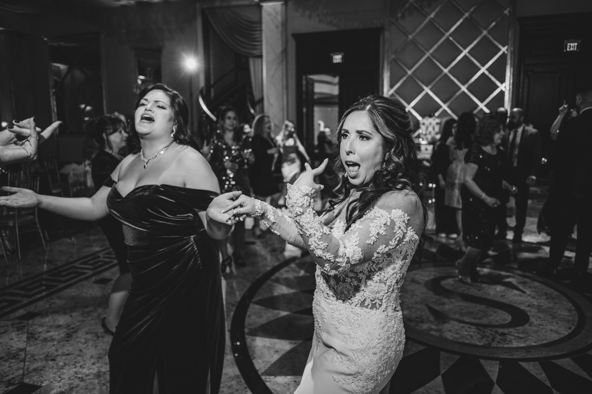 Black and white photo of wedding guests dancing and celebrating at an evening reception.