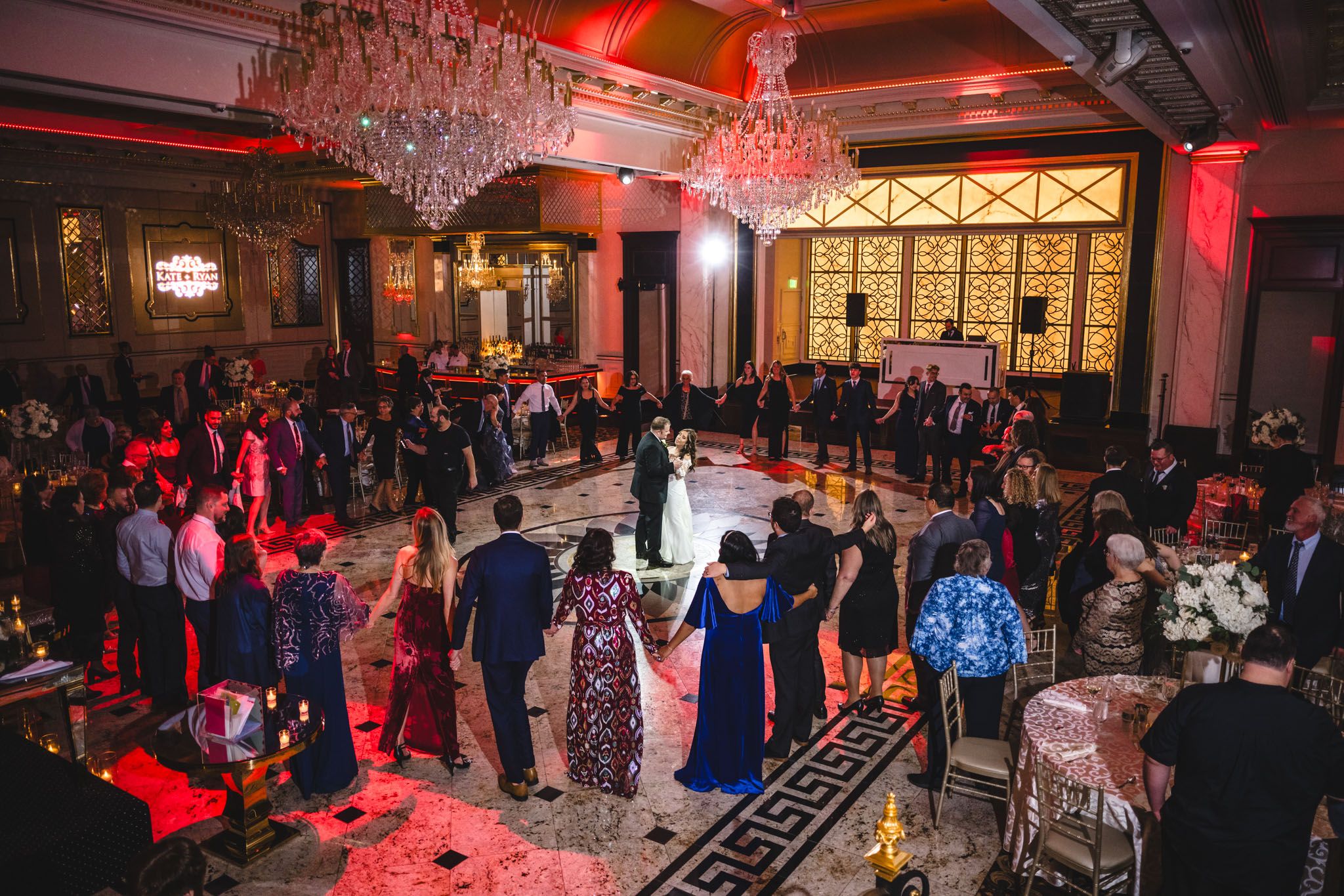Wedding venue illuminated with dramatic red lighting and crystal chandeliers overhead.