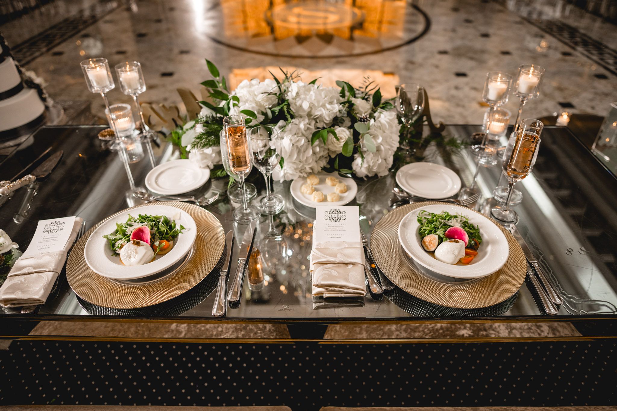 Elegant table settings with white floral centerpieces and glowing candles at a wedding reception.