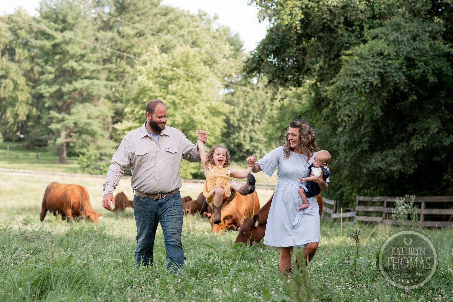 Family walks together on their farm with cattle grazing in the background.