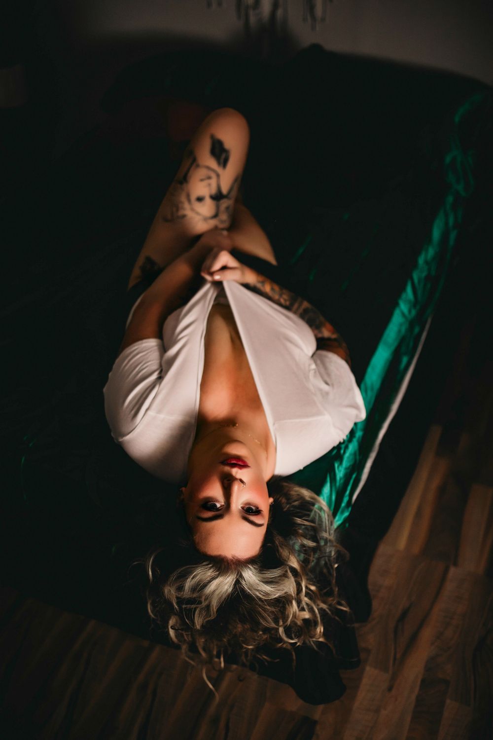 Artistic overhead boudoir photo with natural soft lighting and white top.