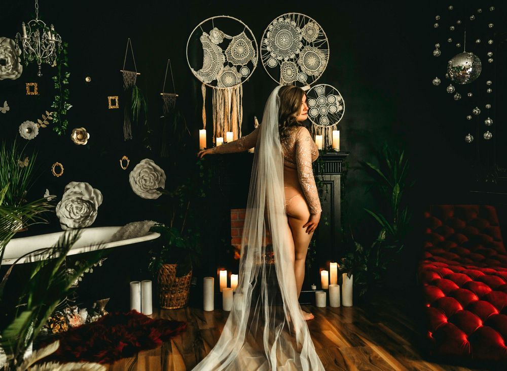A mystical night scene with glowing moon decorations, white drapes, candles, and plants against a dark moody backdrop.