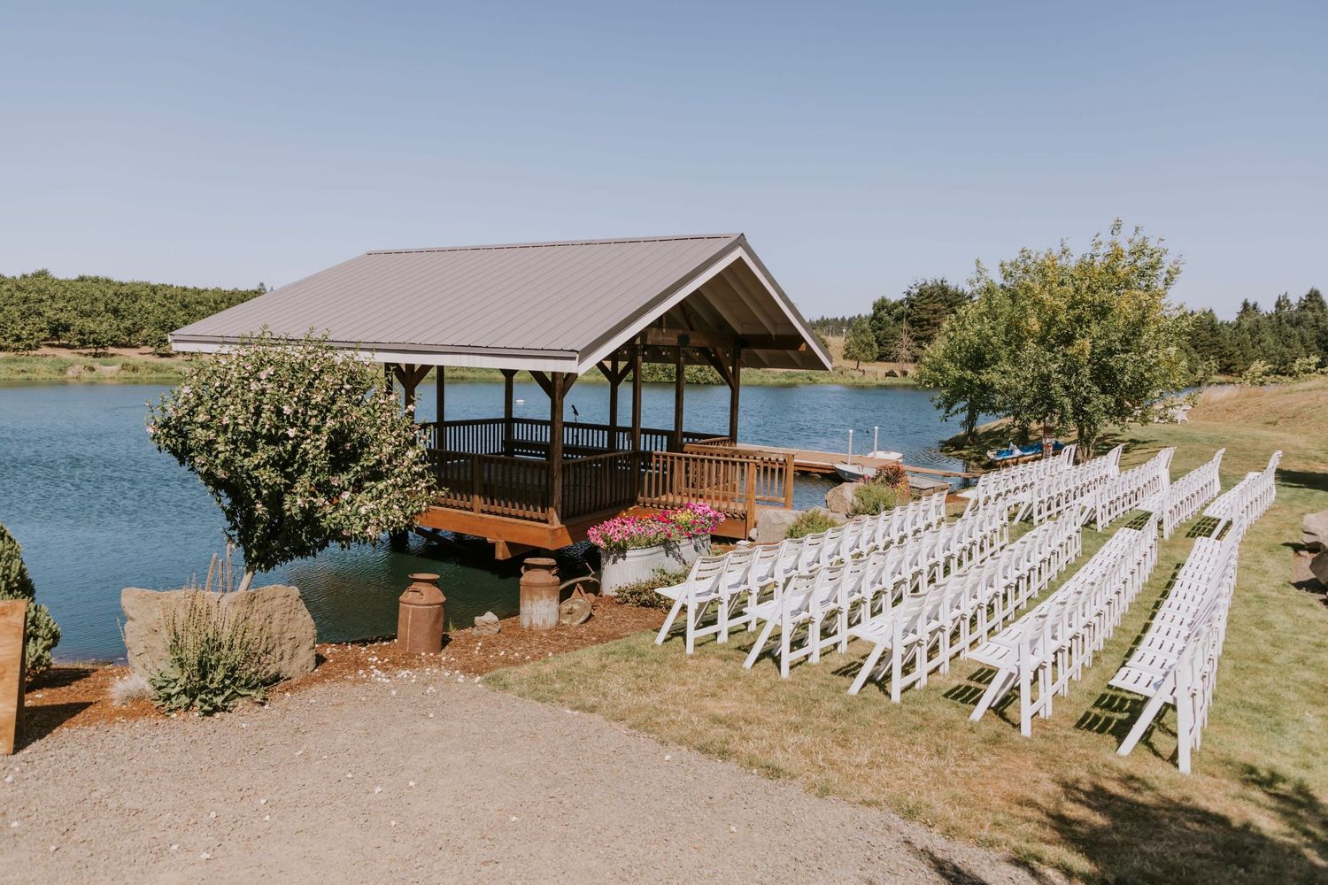 White chairs set up for wedding ceremony in front of pond with big covered dock