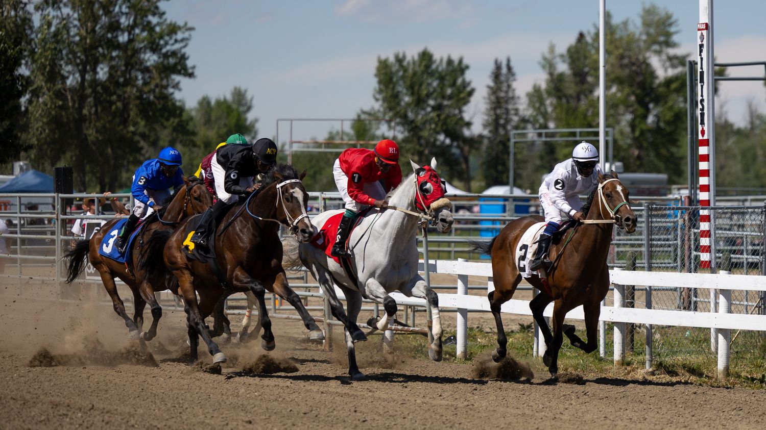 Horse racing action shot showing three jockeys competing on dirt track during race.