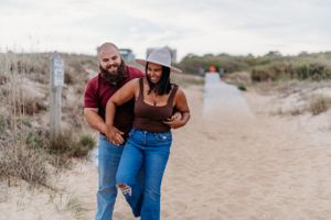 A playful couple enjoying a walk together on a sandy beach path.