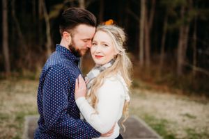 Couple in navy polka dot shirt and white sweater share intimate moment during engagement photoshoot.