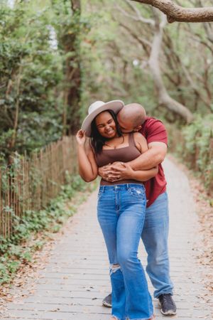 A joyful embrace shared between a couple on a tree-lined walking path.