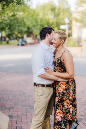 Couple shares intimate moment on brick pathway during outdoor photoshoot.
