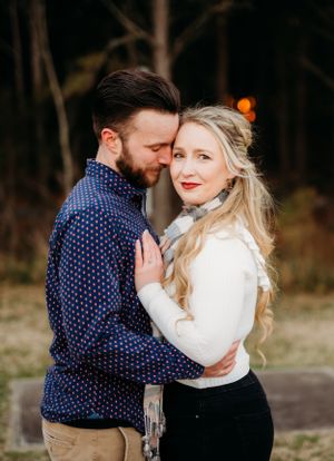 Couple in navy and white share tender moment during outdoor engagement photo session.