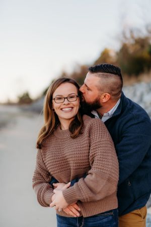 A romantic moment captured between a couple in cozy sweaters during a beach engagement session.