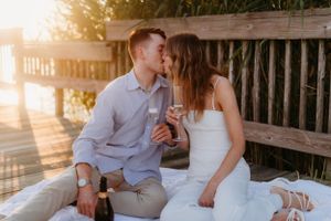 Couple sharing intimate moment on deck with champagne at sunset.