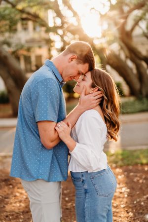 Intimate moment shared between couple under oak trees at golden hour.