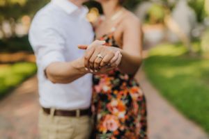 Close-up of couple's hands showing engagement ring during romantic portrait session.