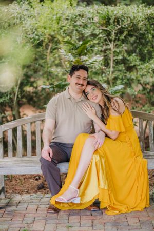 Couple sharing intimate moment on wooden bench in garden setting.