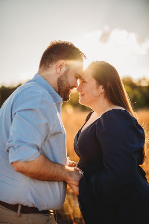 An intimate outdoor portrait of a couple sharing a close moment in the warm sunset light.