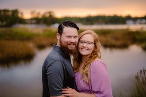 Couple embracing during sunset engagement session by scenic waterfront.