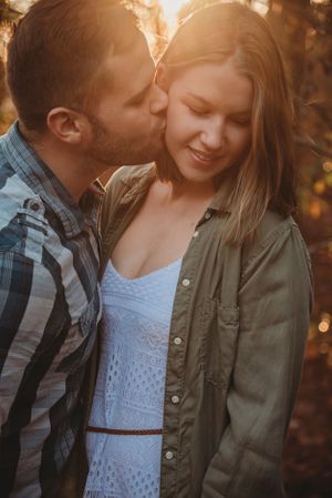 Romantic couple sharing an intimate moment during golden hour in casual outdoor wear.
