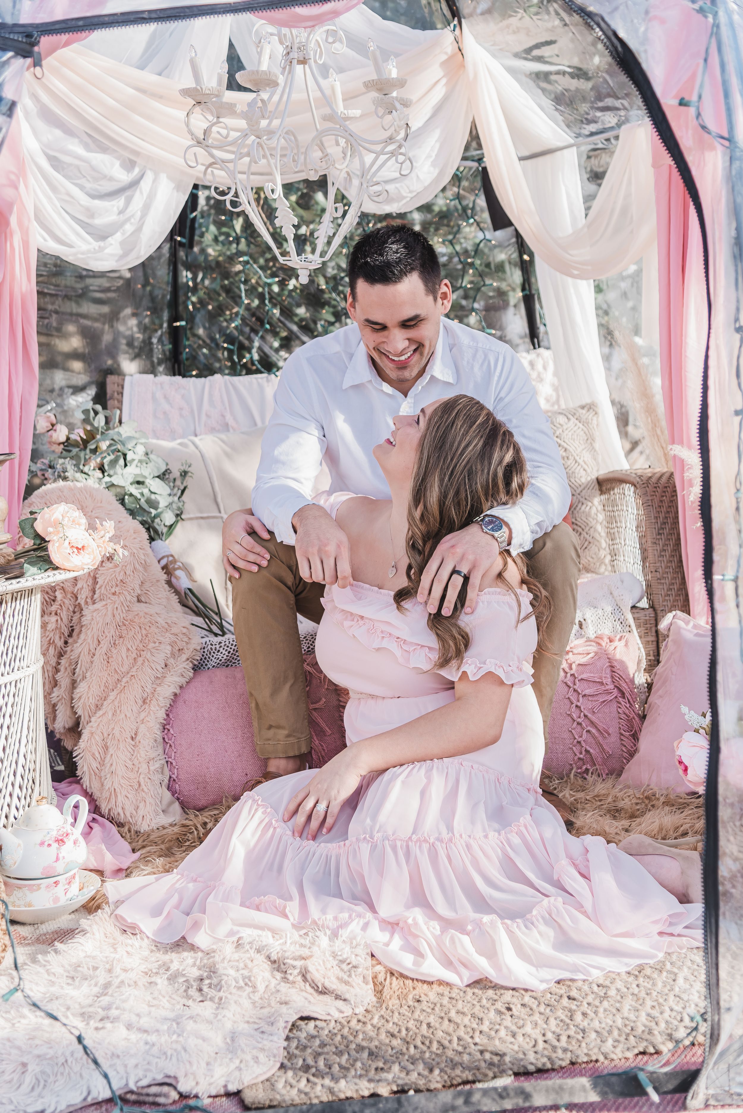 Romantic couple posing in dreamy pink and white decorated tent setting.
