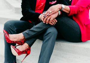 Close up of couple holding hands showing red high heels and formal attire.