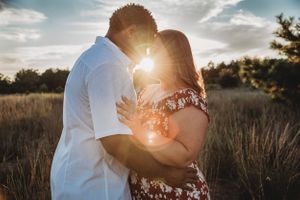 Intimate sunset portrait in a golden field with backlit sky.