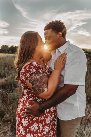 Romantic sunset embrace in a field with golden hour lighting.