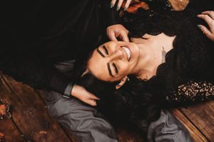 Artistic overhead portrait of someone in black lace lying on wooden surface.