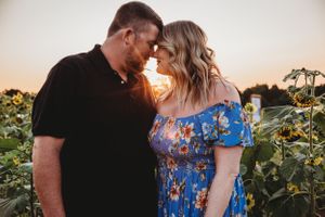 Romantic couple sharing an intimate moment at sunset in a sunflower field.