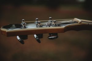 Guitar headstock with tuning pegs photographed in moody lighting.