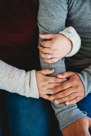 Close-up of hands holding and comforting each other wearing cozy sweaters.