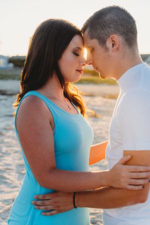 Couple shares romantic moment at sunset on sandy beach.