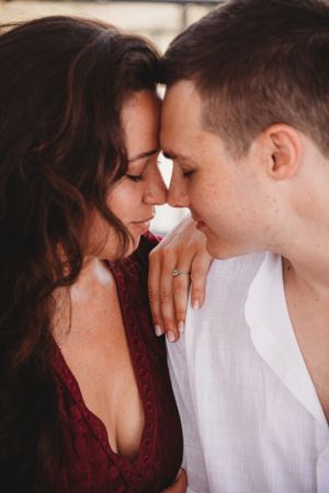 A romantic couple sharing an intimate moment in a warm embrace wearing burgundy and white.