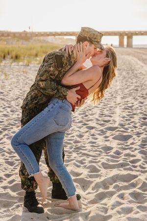 Military service member and partner share romantic moment on beach.