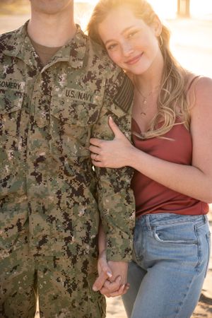 A sunset beach portrait featuring military service member and companion in casual attire.