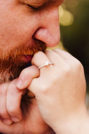 Close up of engagement ring as person kisses hand with delicate diamond band.