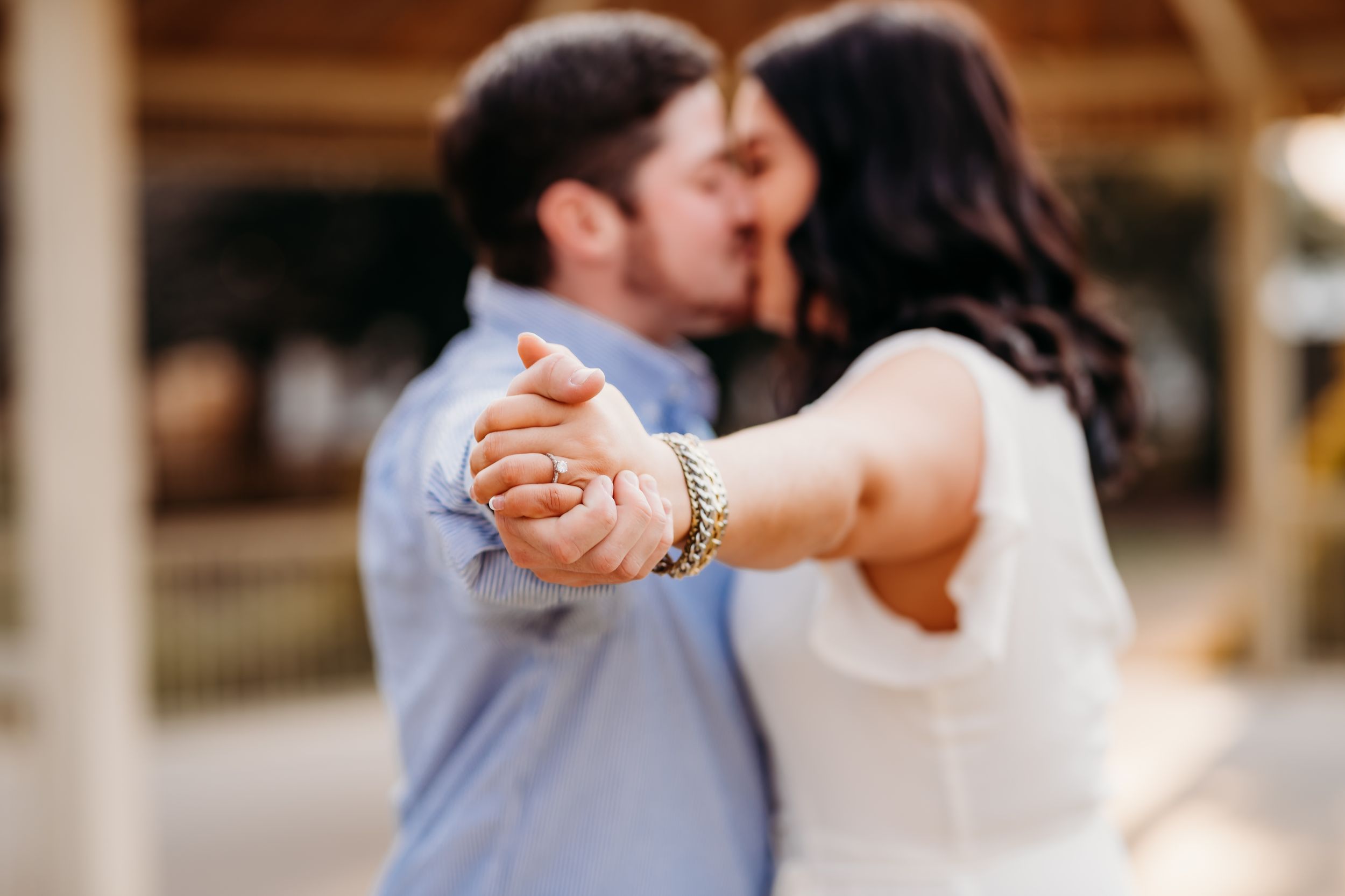 A romantic engagement photo showing a couple dancing together under a wooden pavilion.