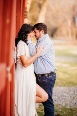 A romantic moment shared between a couple against a rustic red barn backdrop.