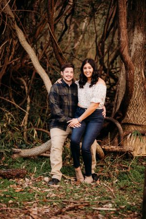 A romantic woodland portrait session featuring a couple posing together on a fallen tree trunk.