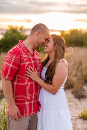 Tender moment between couple during sunset beach photoshoot with natural lighting.