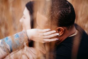 Intimate wedding couple embracing with a tattooed arm and romantic blur effect.