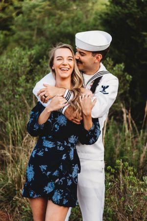 Joyful couple embracing outdoors with one wearing traditional naval uniform.