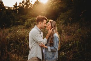 Romantic sunset portrait of couple sharing intimate moment in golden-lit field.