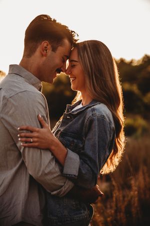 Romantic couple portrait backlit by golden sunset light showing intimate tender moment.