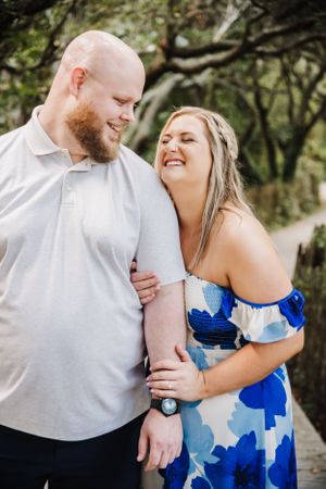 A romantic outdoor couple portrait showing shared laughter and joy while embracing in a natural setting.