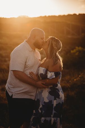 An intimate couple sharing a tender sunset moment together in a golden-lit outdoor setting.