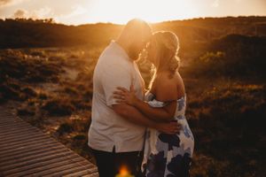 Silhouetted couple embracing during golden sunset.